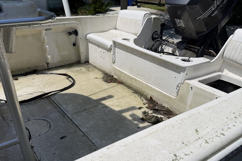 Center-console boat deck before cleaning — stained fiberglass deck and seating
